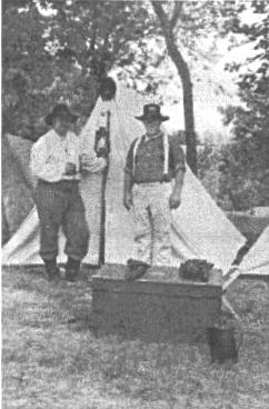 Two men in front of tent with footlocker