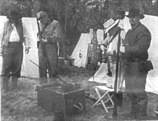 Soldiers checking weapons in front of tents
